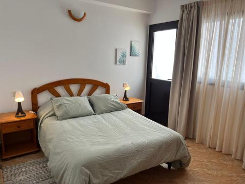 宏达海滩Apartamento Playa Honda的一间卧室配有一张带两盏灯的床和一扇窗户。