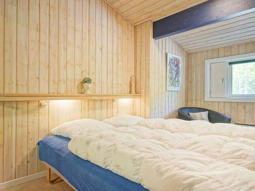 维斯特索马肯Holiday home Nexø XLI的卧室设有木墙和一张大床