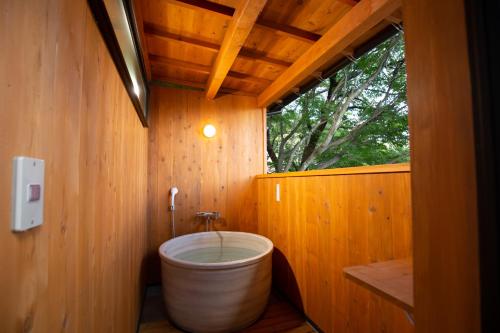 富士河口湖河口湖班乡间别墅酒店的木制浴室设有大浴缸,设有窗户