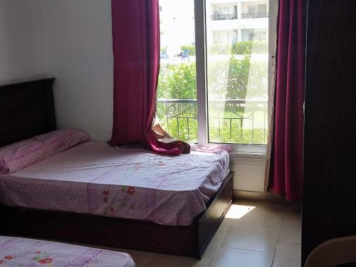 苏伊士palmera el sokhna的一间卧室配有床和一个带粉红色窗帘的窗户。