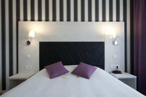 图瓦里伊特莱尔旅馆的一间卧室配有一张带紫色枕头的大床