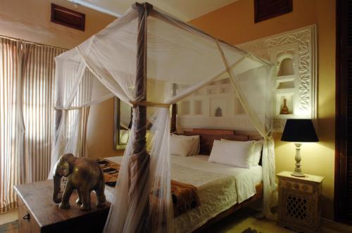 坎帕拉科洛洛别墅的一间卧室配有一张天蓬床和一头象雕像