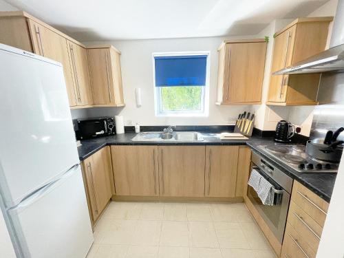 法恩伯勒Travaal - 2 Bed Serviced Apartment Farnborough的厨房配有木制橱柜和白色冰箱。
