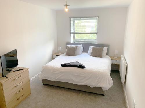 法恩伯勒Travaal - 2 Bed Serviced Apartment Farnborough的一间白色卧室,配有床和电视