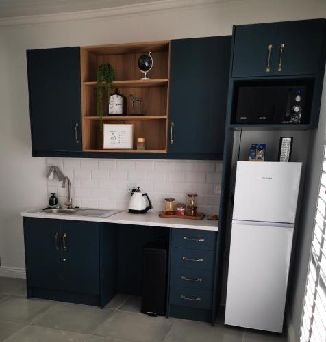 布隆方丹10 Jock Meiring Guesthouse Unit 2的厨房配有蓝色橱柜和白色冰箱