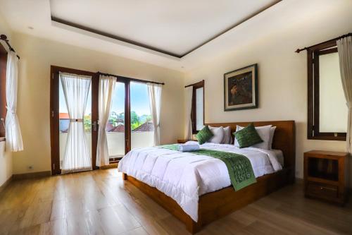 乌布Central Ubud Modern Apartments + Private Kitchen的一间卧室配有带白色床单和绿色枕头的床。