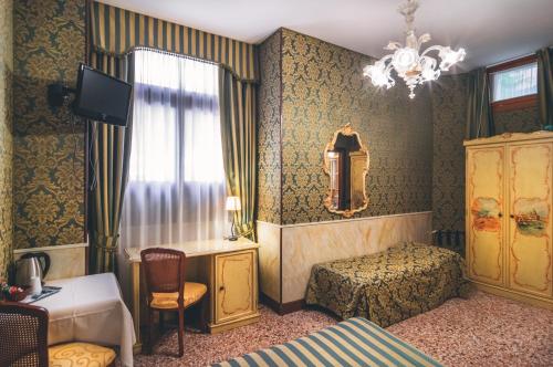 威尼斯艾尔马尔卡通酒店的一间卧室配有一张床、一张书桌和一个窗户。