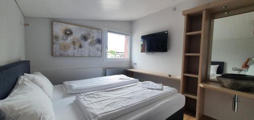 因特拉肯The River Village的一间卧室配有一张带两张白色床单的床和电视。