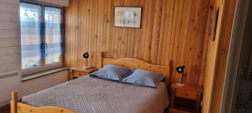 新拉巴蒂La Rotonde des Grânes的一间卧室配有一张带木墙和窗户的床。