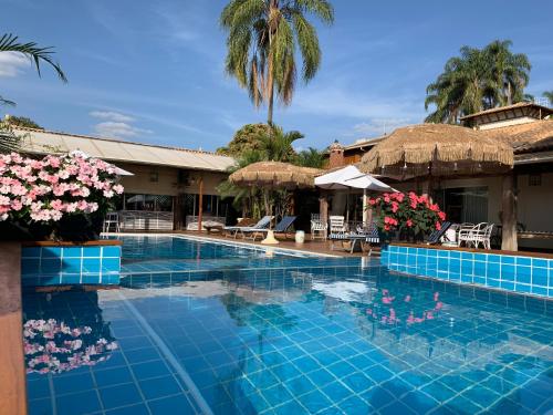 布罗塔斯Villa Maria Pousada de Charme的一座带鲜花和遮阳伞的度假村游泳池