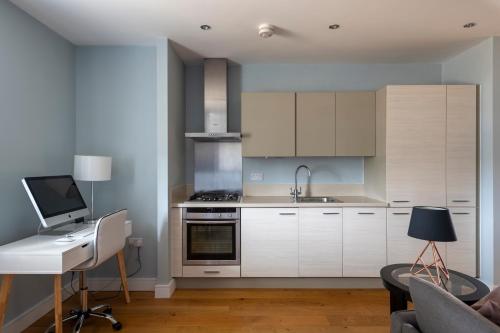 布伦特里Luxurious Private One Bedroom Apartment的厨房配有白色橱柜和带电脑的书桌