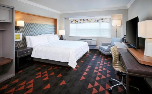 奥克维尔Holiday Inn & Suites Oakville at Bronte, an IHG Hotel的酒店客房配有一张床、一张书桌和一台电视。