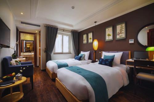 河内Hotel Emerald Waters Classy的酒店客房,配有两张床和椅子