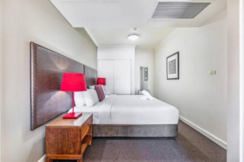 达尔文'Esplanade Ease' A Resort Balcony Pad with Pool的一间卧室配有一张床和一张桌子上的红灯