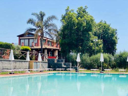 Aci SantʼAntonioAgricampeggio Verde Etna的房屋前方的大型游泳池配有遮阳伞