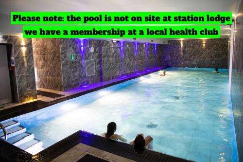温德米尔Station Lodge - FREE off-site Health Club access with Pool, Sauna, Steam Room & Gym的水中一个游泳池,有两人坐在那里
