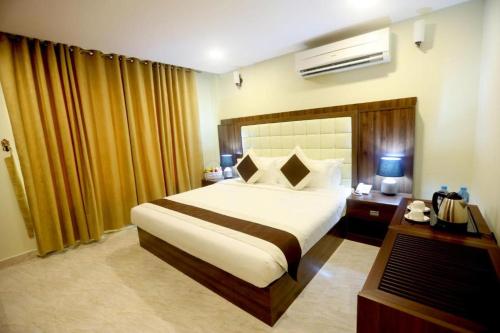 锡卜Golden Crown Hotel Alseeb Muscat的酒店客房配有一张床和一张书桌及一台电视