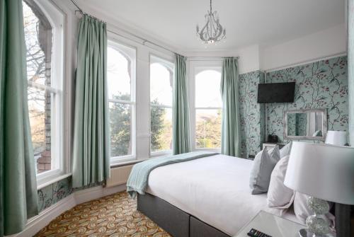 利物浦塞夫顿公园酒店的一间卧室配有一张带绿色窗帘和窗户的床。