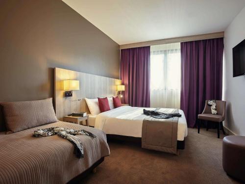 勒谢奈Mercure Versailles Paris Ouest的酒店客房,配有两张床和椅子