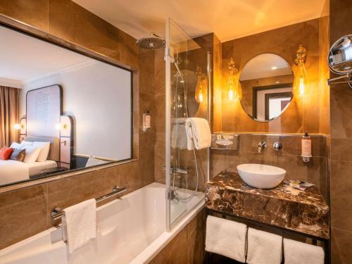 勒谢奈Mercure Versailles Paris Ouest的带浴缸、水槽和镜子的浴室