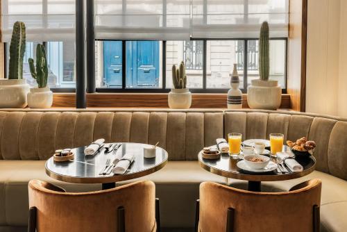 巴黎Pavillon Faubourg Saint-Germain & Spa的沙发上两张桌子,上面摆放着食物和饮料