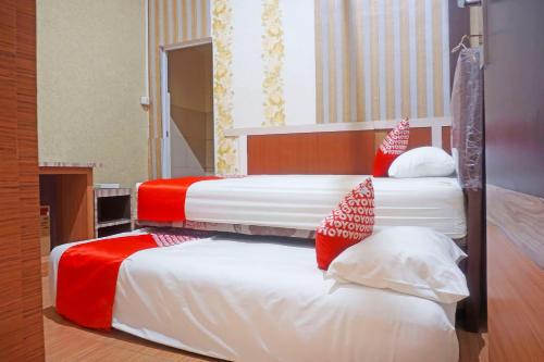 JenepontoOYO 91433 Hotel Sari Jeneponto的两张位于酒店客房的床,配有红色和白色枕头