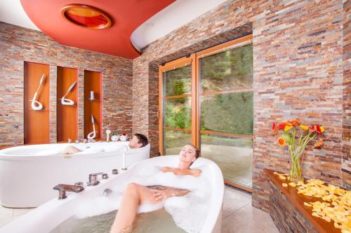 兹林考斯特莱科温泉酒店的坐在浴室浴缸里的男人