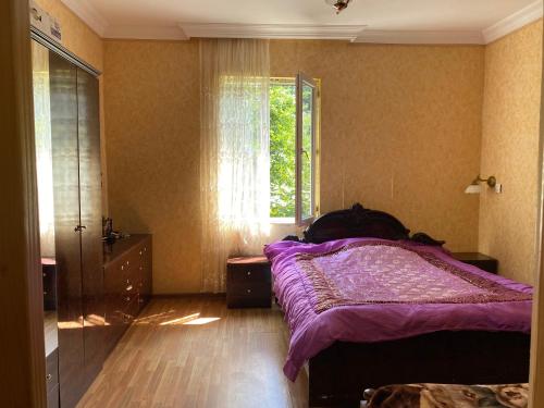 巴统Venera's Guest House的一间卧室设有紫色的床和窗户
