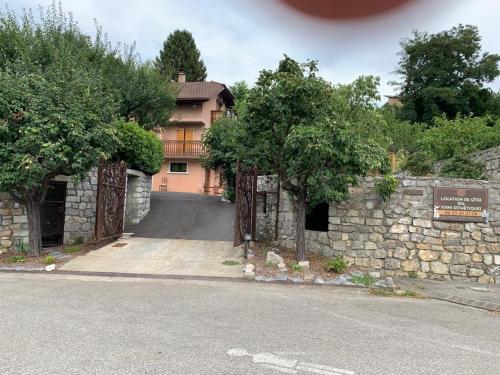 瓦戈兰斯appartement avec Jacuzzi hammam sauna privatisé au rez de chaussée ds maison à Voglans à 2 kilomètres du lac du bourget en Savoie entre Chambéry et Aix les Bains cure thermale的石墙和车道的房子