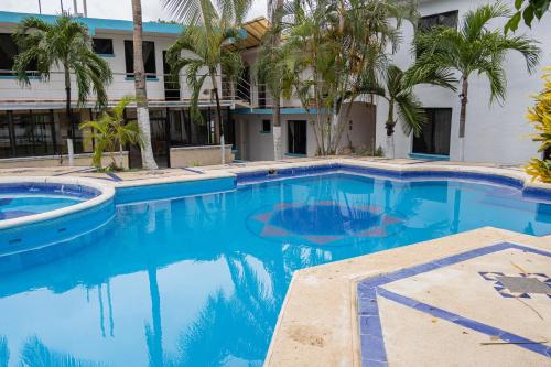切图马尔OYO Hotel Marías,Aeropuerto Internacional de Chetumal的一座大型游泳池,在一座建筑前种有棕榈树