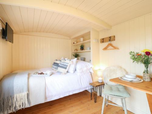 阿什伯恩High Grounds Shepherd's Hut的卧室配有白色的床和桌子