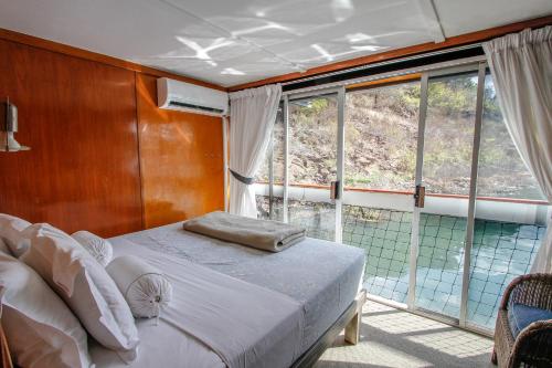 焦济尼Shayamanzi Houseboats的卧室在窗户前配有一张床