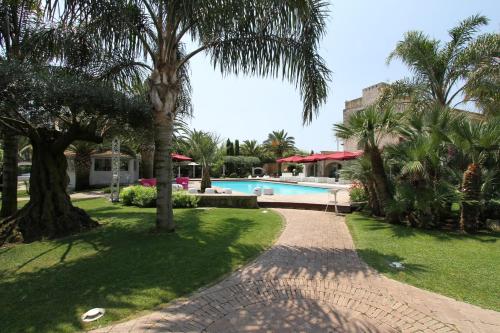 蒙德拉戈内Hotel & Resort Lunatenuta的一个带游泳池和棕榈树的度假庭院