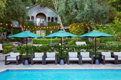 Kenwood肯伍德酒店&Spa中心的房屋旁的游泳池配有椅子和遮阳伞