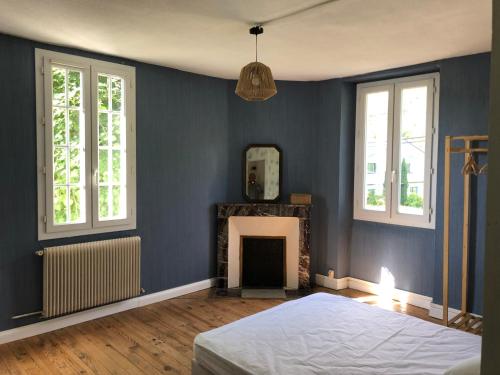 JurançonPetite maison avec terrasse的蓝色卧室设有一张床和一个壁炉