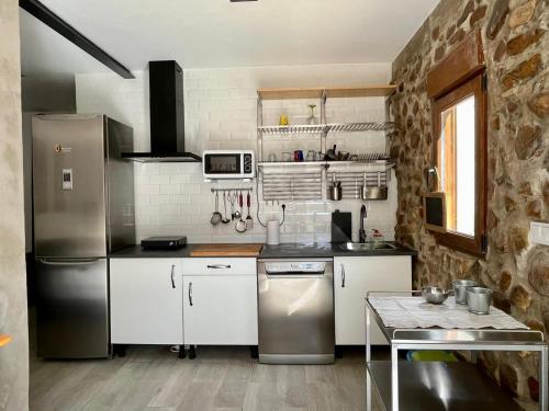 UcedaStone Garden, Casa en plena naturaleza的厨房配有白色橱柜和不锈钢冰箱