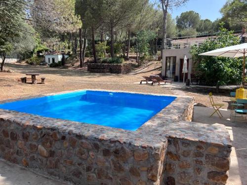 UcedaStone Garden, Casa en plena naturaleza的庭院旁石墙中的游泳池