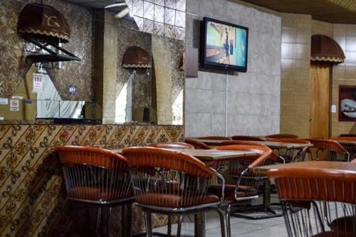 拉普拉塔Hotel Acuarius的一间带桌椅和电视的餐厅