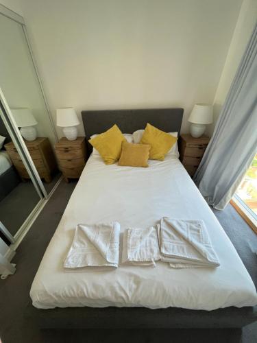 贝尔法斯特City Centre Luxury Apartments的一间卧室配有带白色床单和黄色枕头的床。