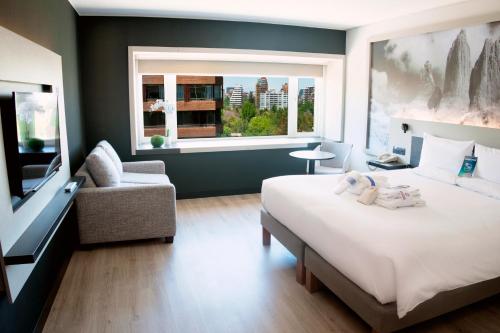 圣地亚哥圣地亚哥维塔库拉诺富特酒店的一间卧室配有一张床、一张沙发和一个窗口