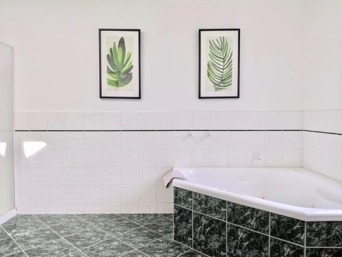 仙女港Pea Soup Cottage的浴室设有浴缸,墙上挂有两张画框