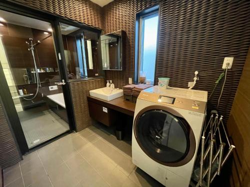 福冈Luxury Villa Saitozaki UMIHOTARU的一间带洗衣机和水槽的浴室