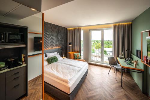 柏林LOGINN Hotel Berlin Airport的一间卧室配有一张床、一张书桌和一个窗户。