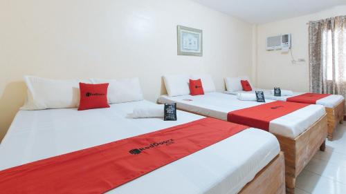 UrdanetaRedDoorz @ Goldland Spring Resort Urdaneta City的配有红色和白色床单的客房内的三张床