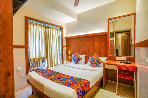 孟买FabExpress Super 7 Inn的一间卧室配有一张床、一张书桌和一面镜子