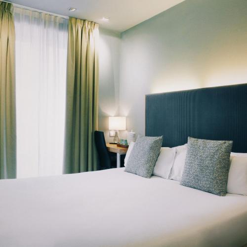 马德里珀蒂宫特雷斯克鲁塞斯高科技酒店的卧室配有一张大白色床和窗户