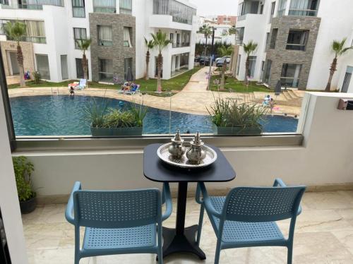阿加迪尔Hivernage, Superbe appartement dans une résidence的享有泳池美景的阳台配有桌椅。