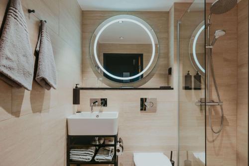 朗伊尔城方垦小屋酒店的一间带水槽、镜子和淋浴的浴室