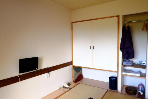 富士河口湖作弥宾馆的一间设有白色橱柜和电视的客房
