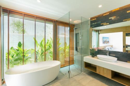 邦涛海滩Ananas villa Shambala grand Cherng Talay的一间带两个盥洗盆和浴缸的浴室以及大窗户。